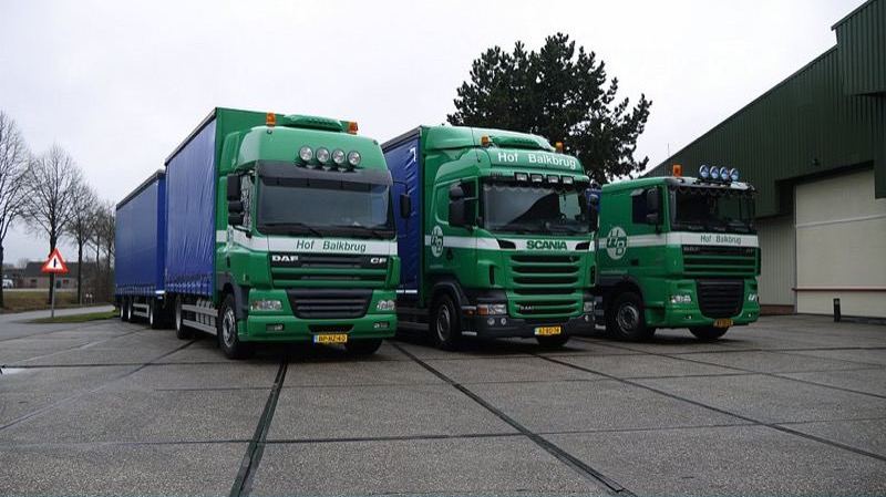 Drie vrachtwagens van Hof Balkbrug bij de bedrijfsloods, het complete wagenpark
